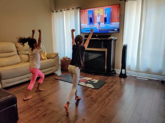 2 kids exercising infront of a tv