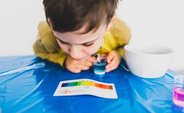 a boy looking at a color chart and is about to do a science experiment