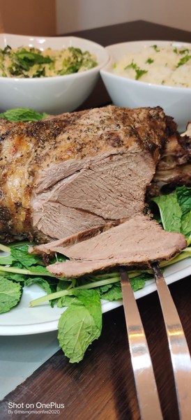 sliced leg of lamb on a platter on a bed of spinach
