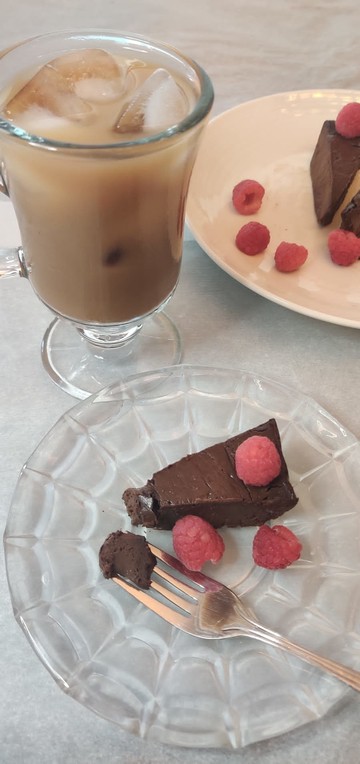 No bake chocolate cake slice on a plate with raspberries and iced coffee