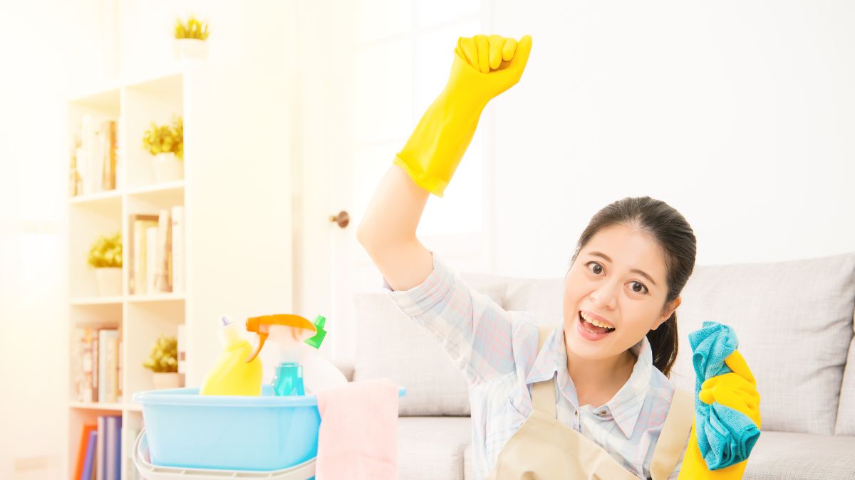 woman with fist in air with cleaning products and rubber gloves on