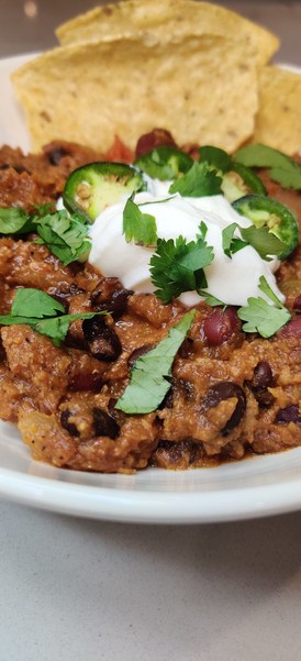 garnished turkey chili with sour cream, cilantro and jalapeno peppers