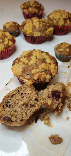 cranberry orange muffins spread on the counter.  The front muffin is cut open.