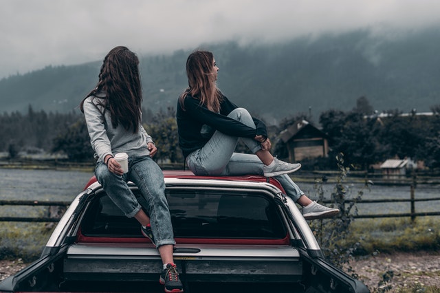 2 girls sitting on top of a car