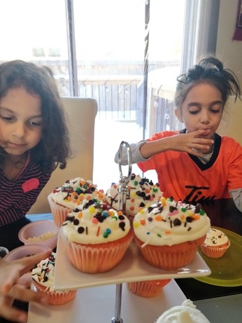 girls decorating the pink velvet cupcakes