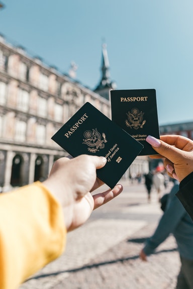 two people's hands holding 2 passports