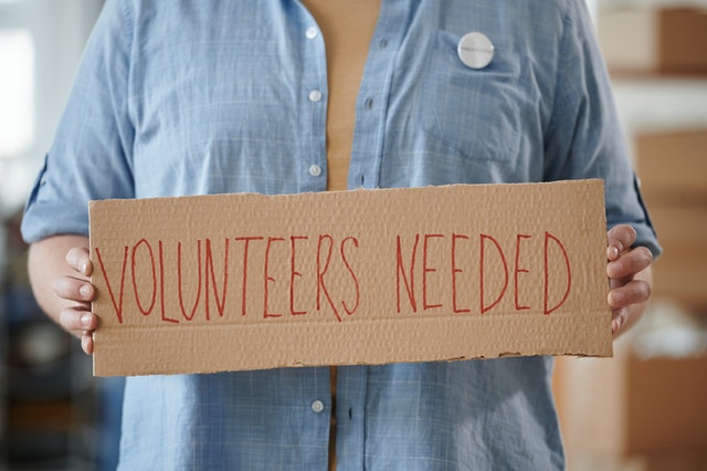 person holding volunteers needed sign