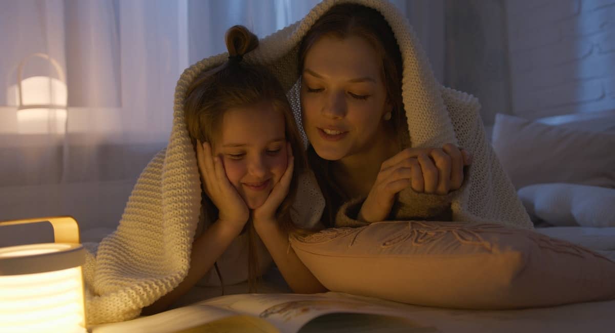 mom and daughter reading together at night.