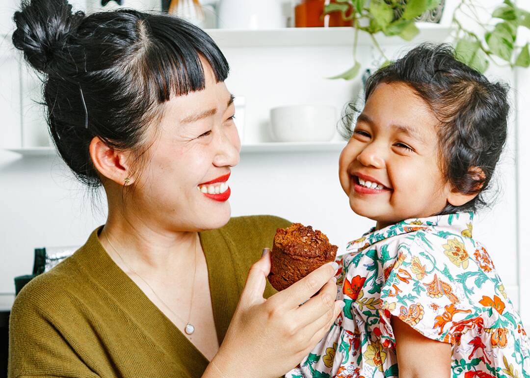 mom holding daughter, eating plant-based, kid-friendly snacks