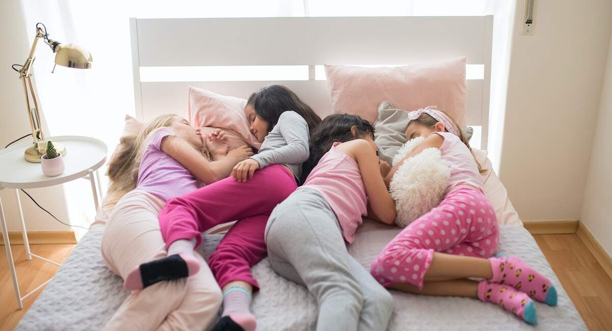 four girls sleeping in a bed