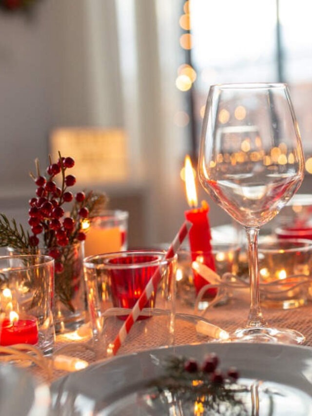 table setting with red candles, wine glasses and holiday decor