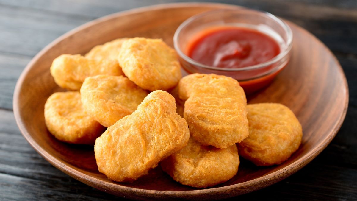 chicken nuggets in a bowl with ketchup.