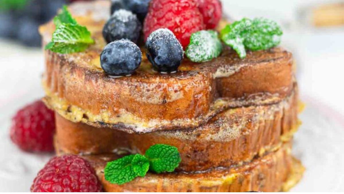french toast in layers on a plate with berries on top.