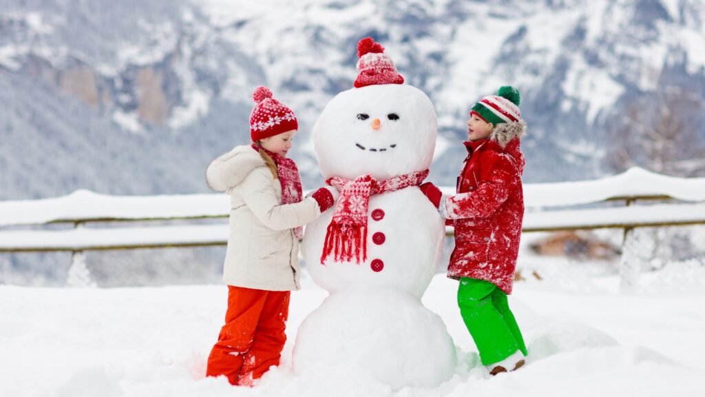 a boy and a girl building a snowman.