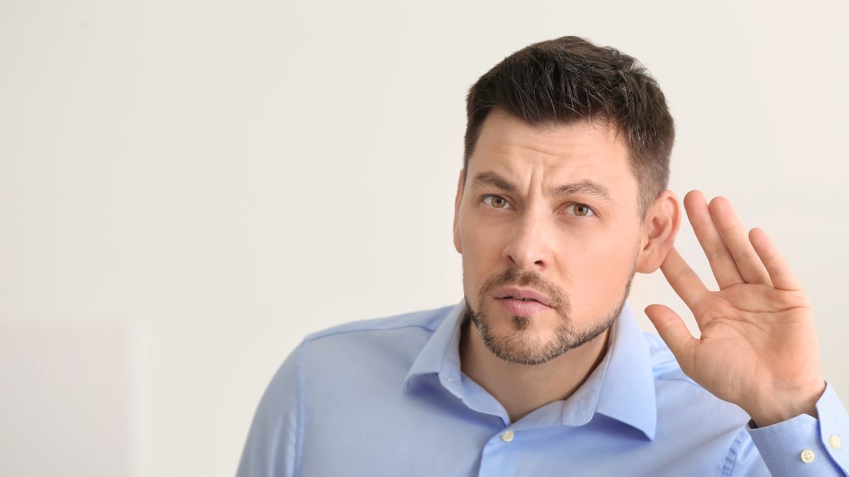 man with hand up to ear like he can't hear