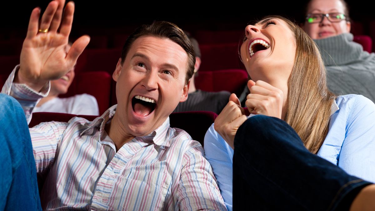 man and woman laughing in a theatre while watching a movie