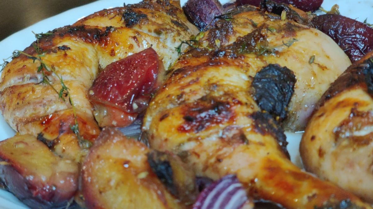 roasted chicken on a platter with plums and onions