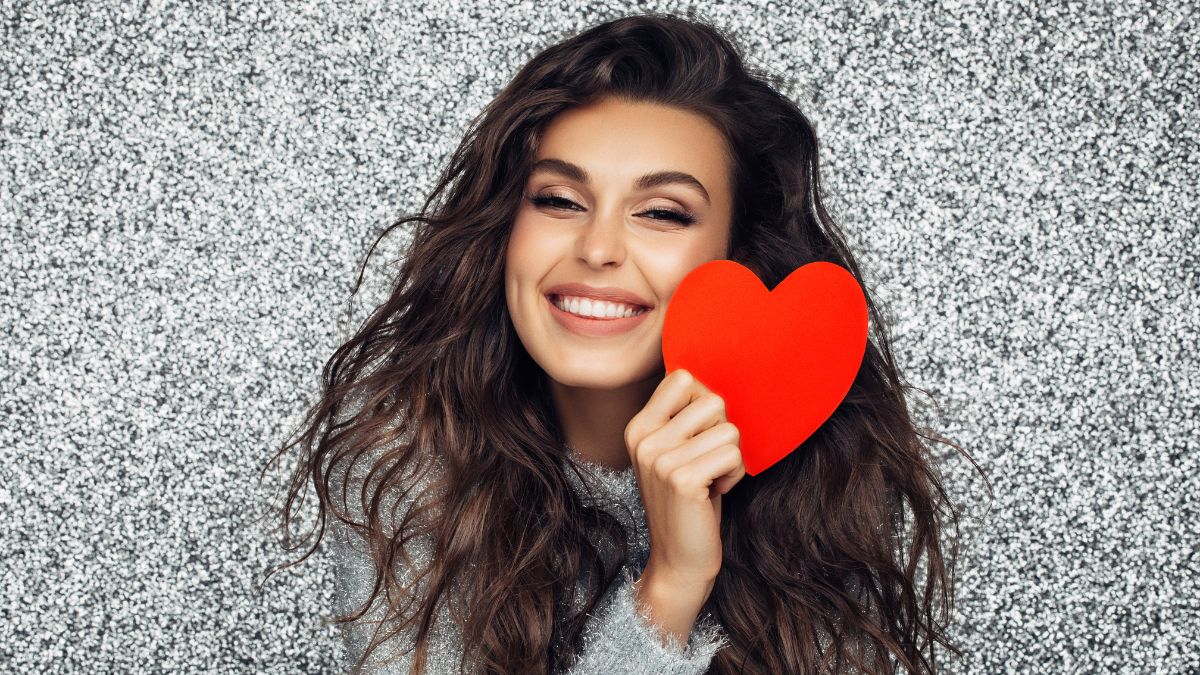 woman smiling and holding a red heart