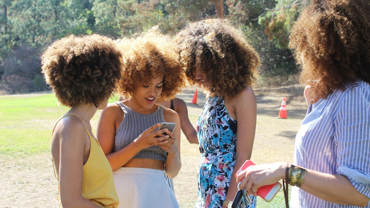 woman looking at a cellphone with a three women around her