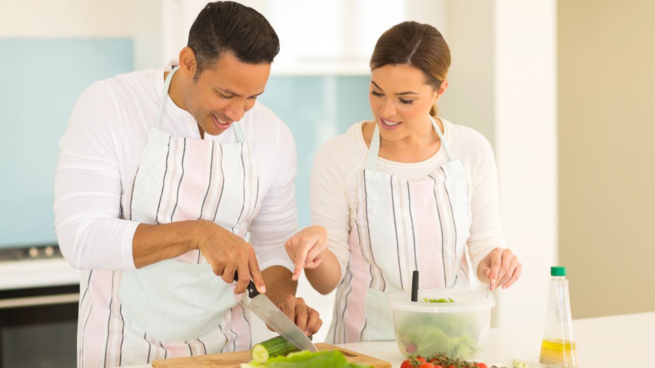 woman showing man how to cut vegetables