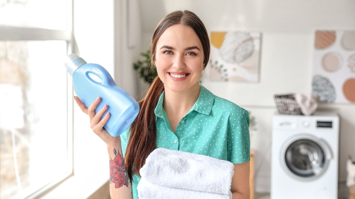 woman holding laundry detergent and towels