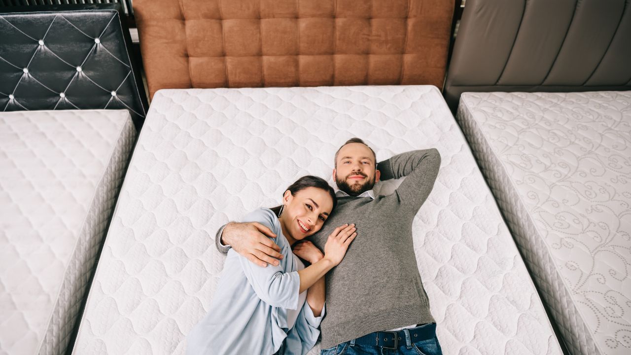 man and woman lying down on a mattress in a store