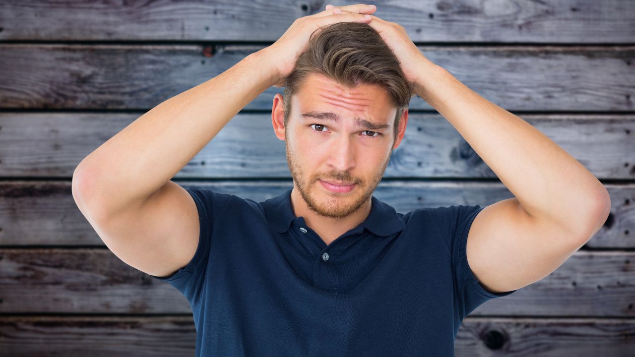 man with both hands on top of head looking confused