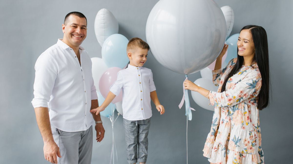 man, woman and son holding a balloon to reveal the baby's gender.