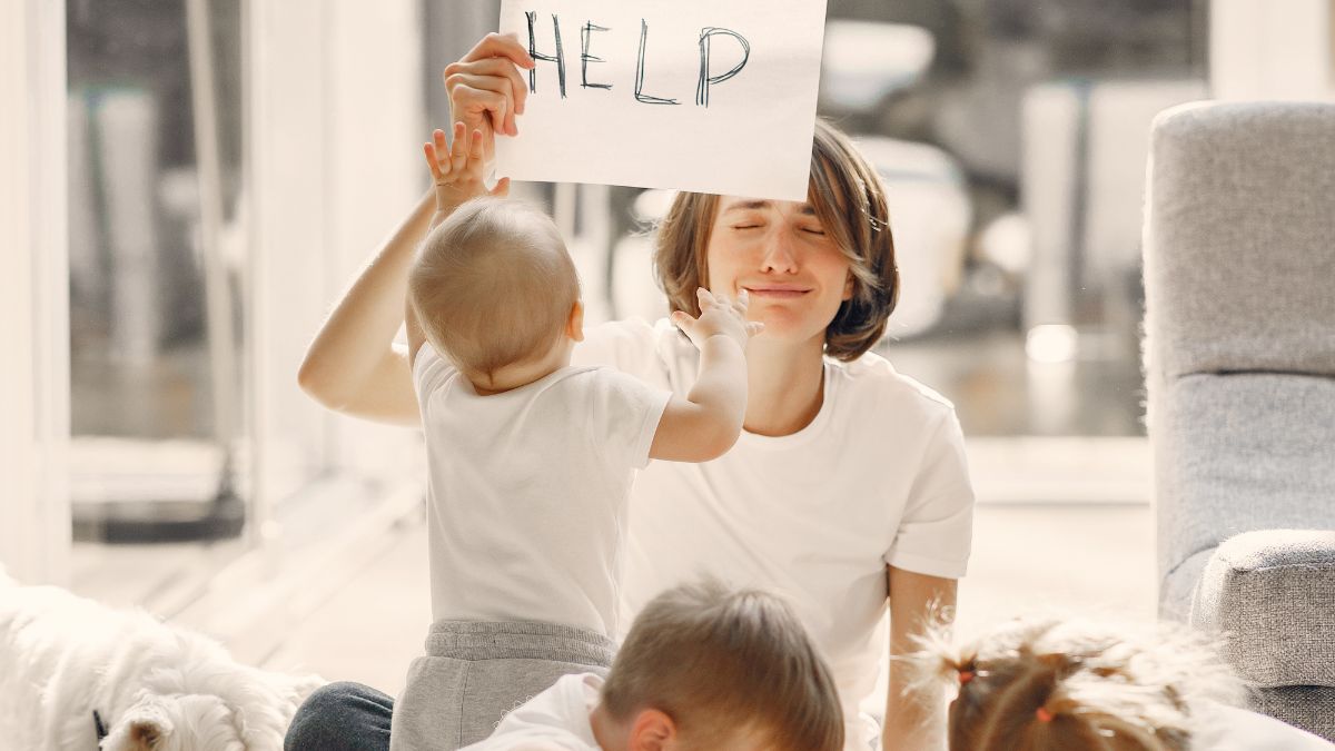 a tired mom with three kids holding up a help sign
