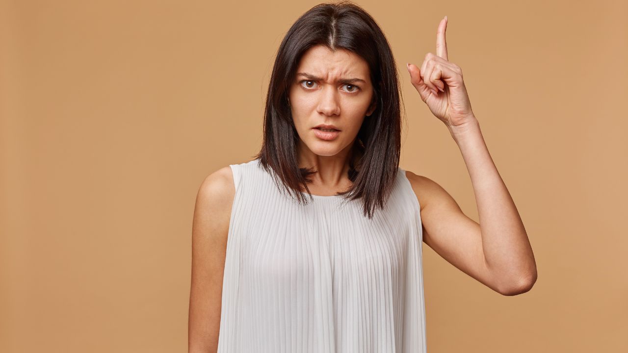 woman with finger up looking serious demanding something