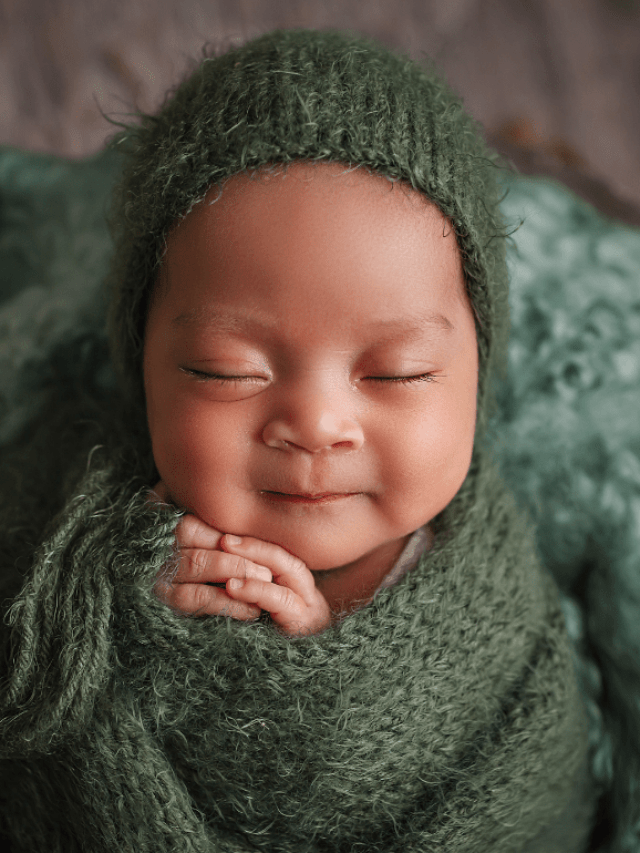 a baby swaddles in a green blanket.