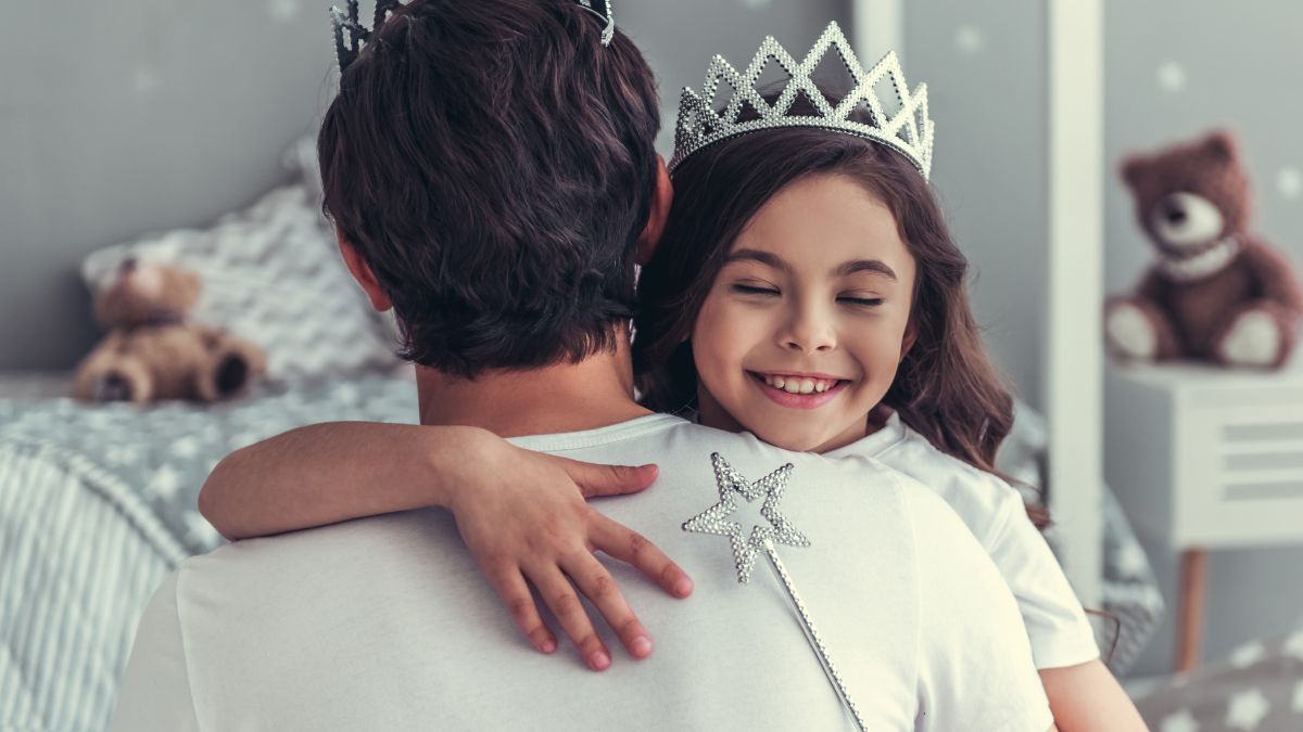 dad holding daughter with tiara on
