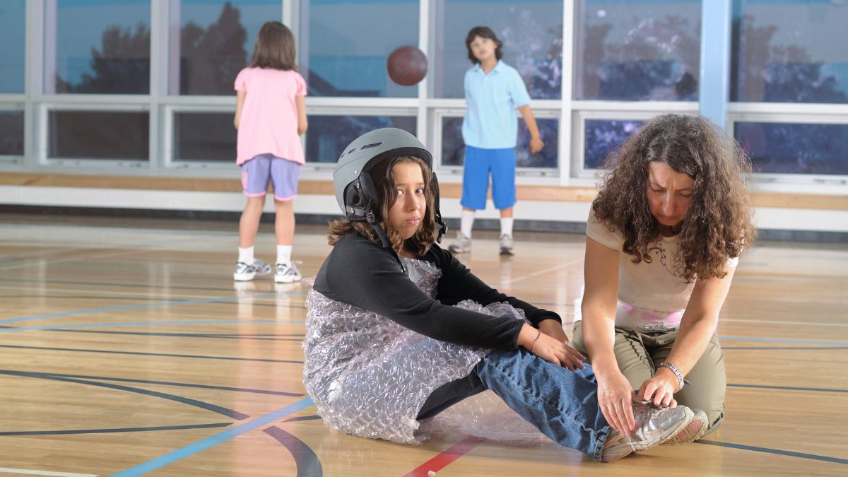 girl wearing a helmet while her mom ties her shoes