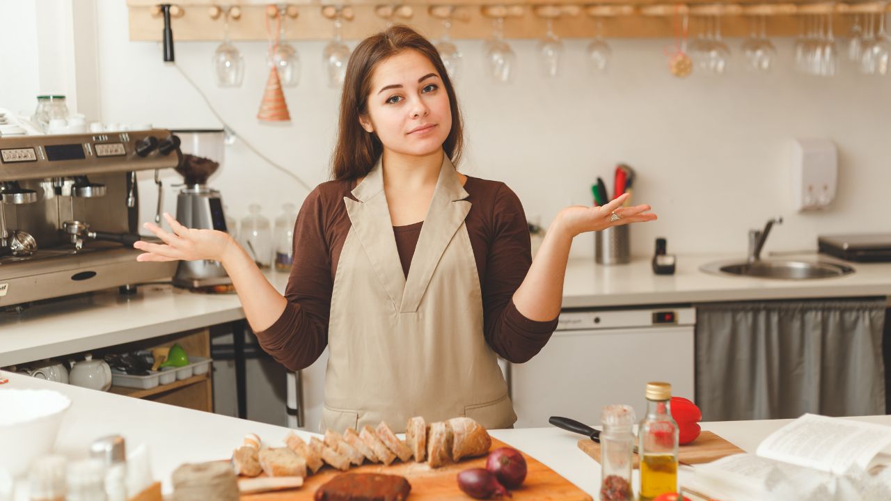 woman cooking in the kitchen frustrated with hands up, bread on the counter.