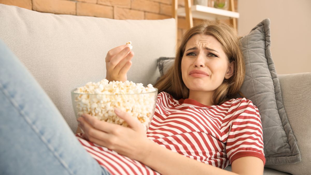 woman crying while watching a movie and eating popcorn,