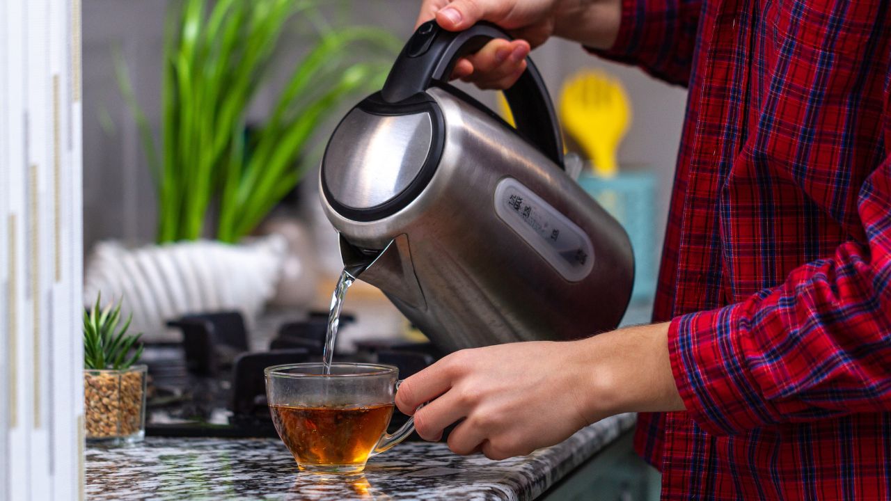 person pouring hot water from electric kettle
