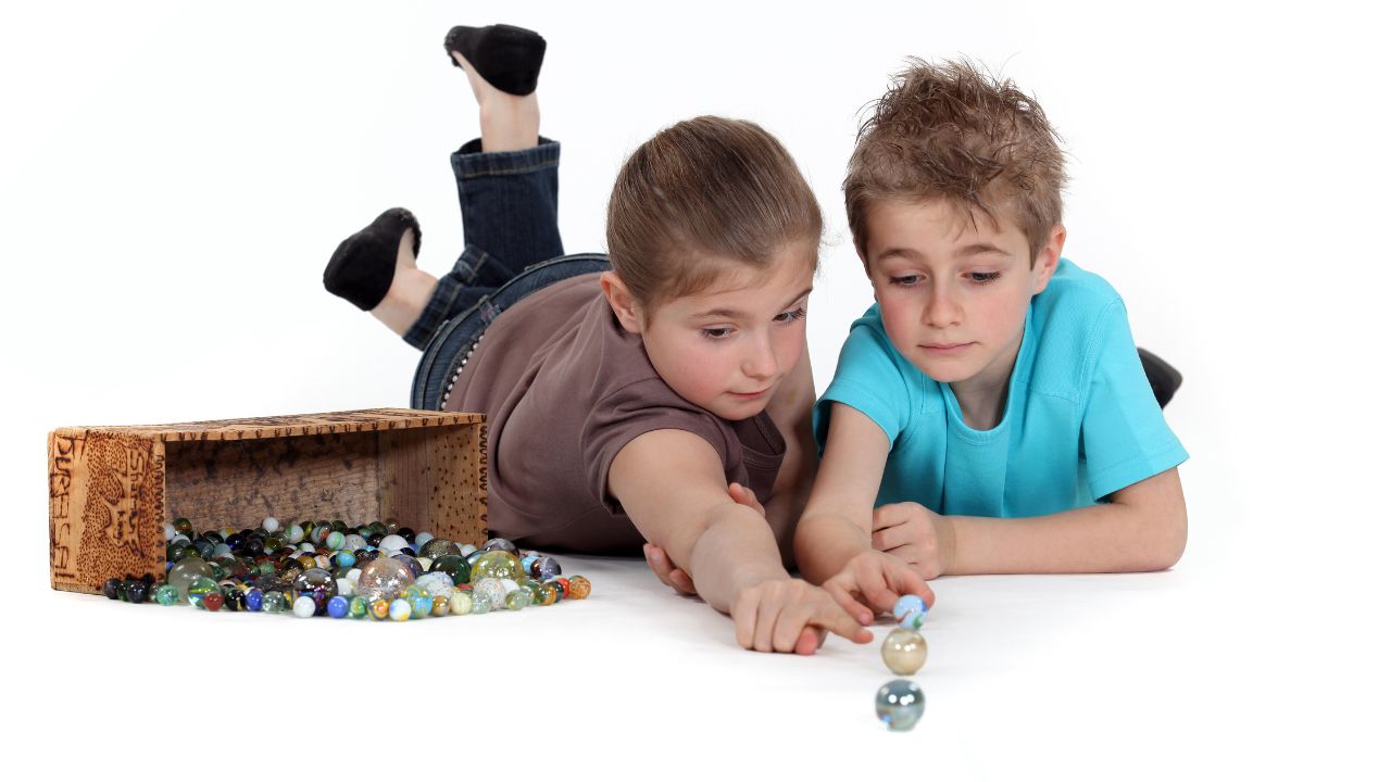 a boy and girl playing with marbles on the ground