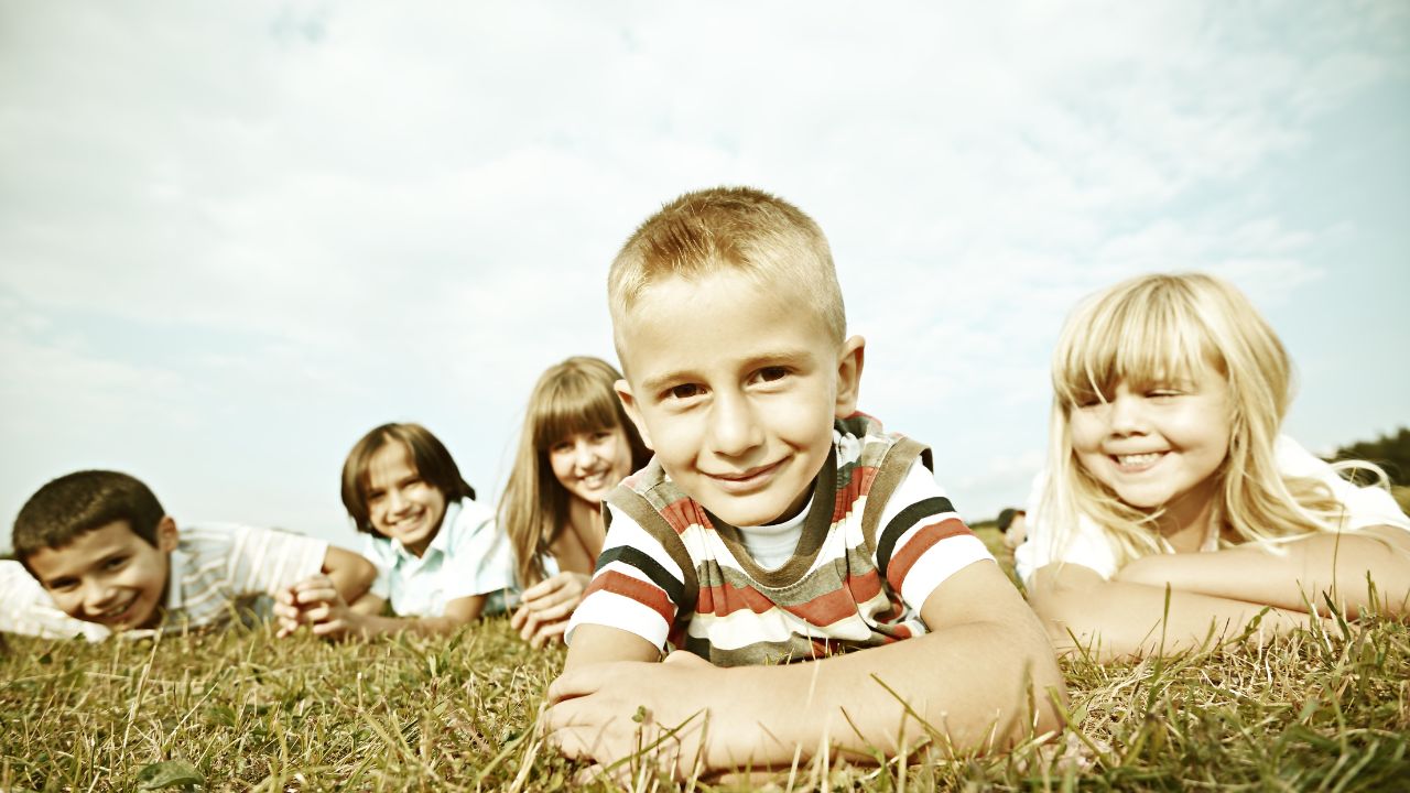 kids playing outside, lying on the grass smiling
