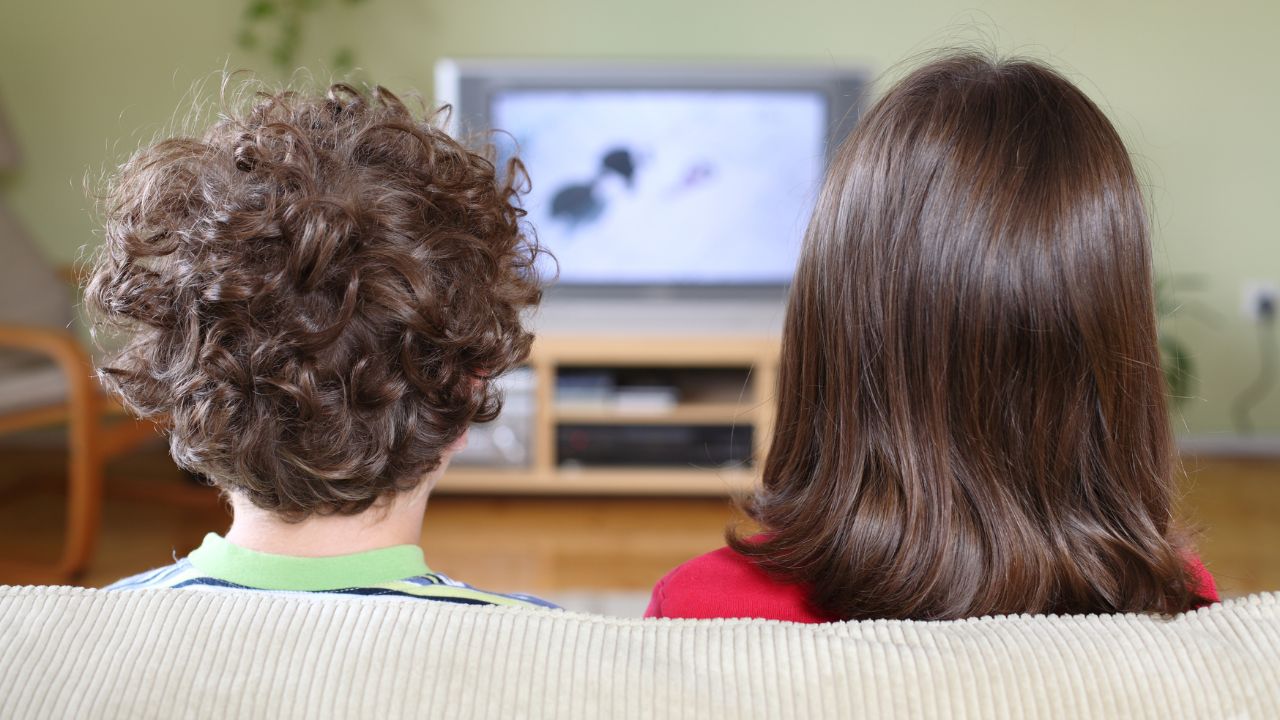 the back of the head of a boy and girl watching tv