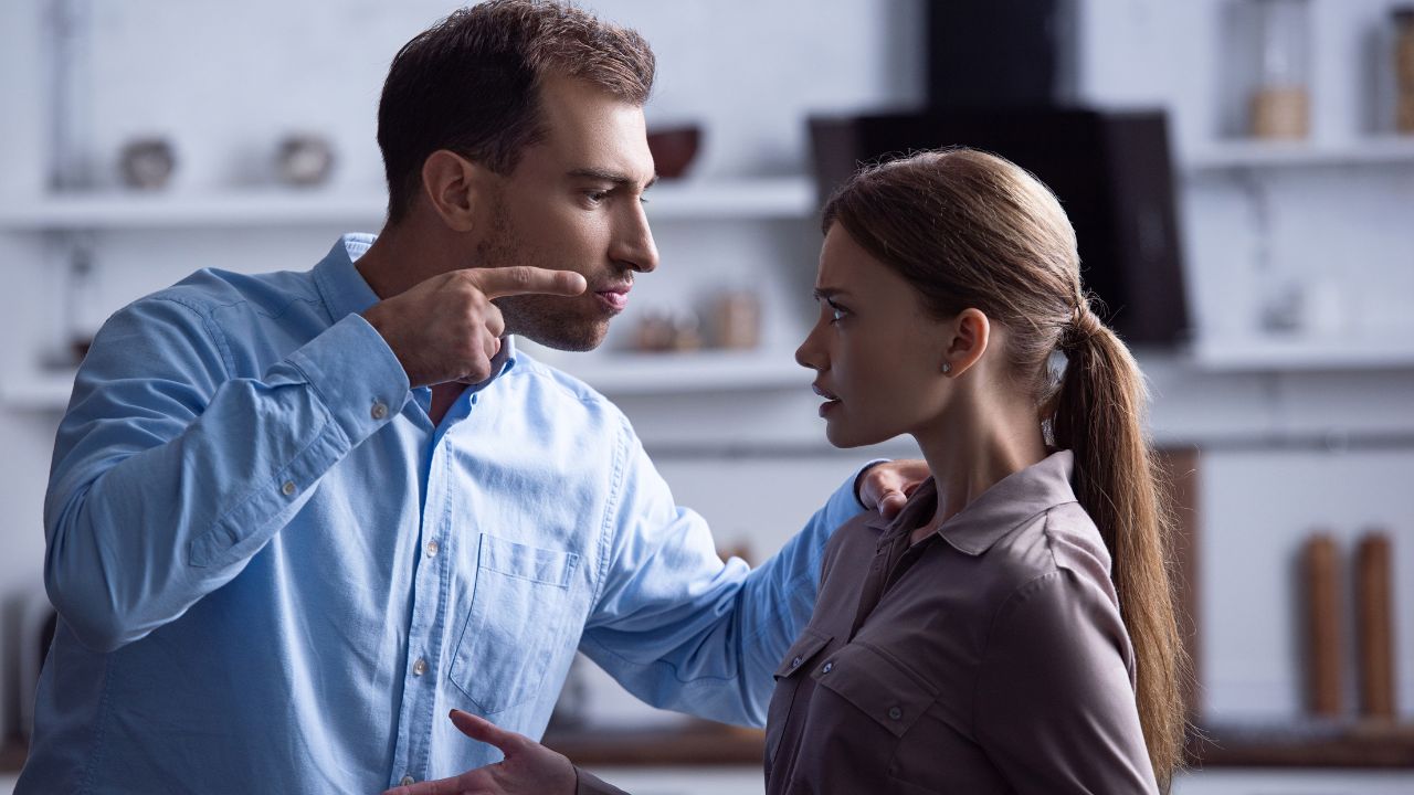 man pointing finger and has hands on woman in an abusive way