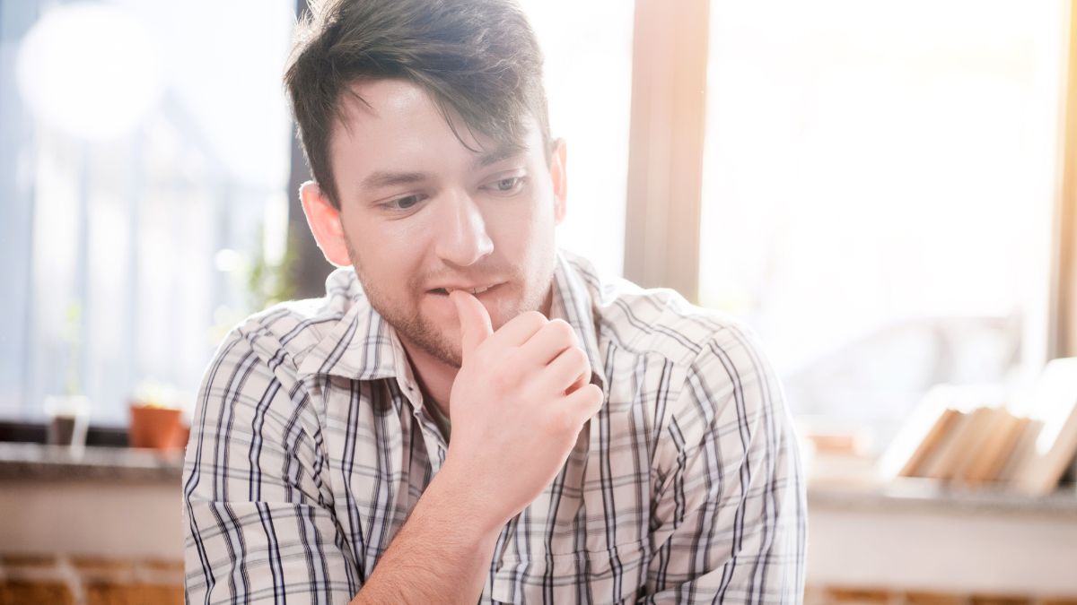 man with tip of thumb in mouth, deep in thought