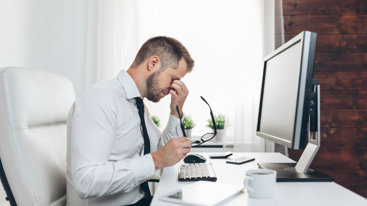 a man in front of a computer in his office looking tired