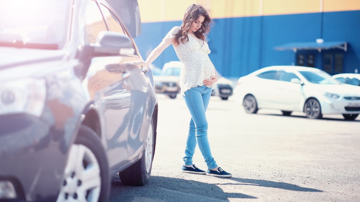 pregnant woman standing beside a car.