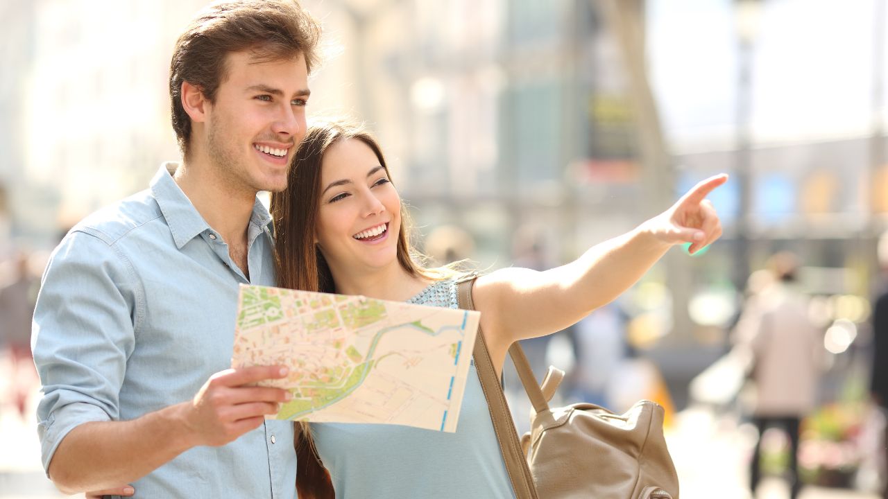 a woman is pointing somewhere while beside a man who is holding a map