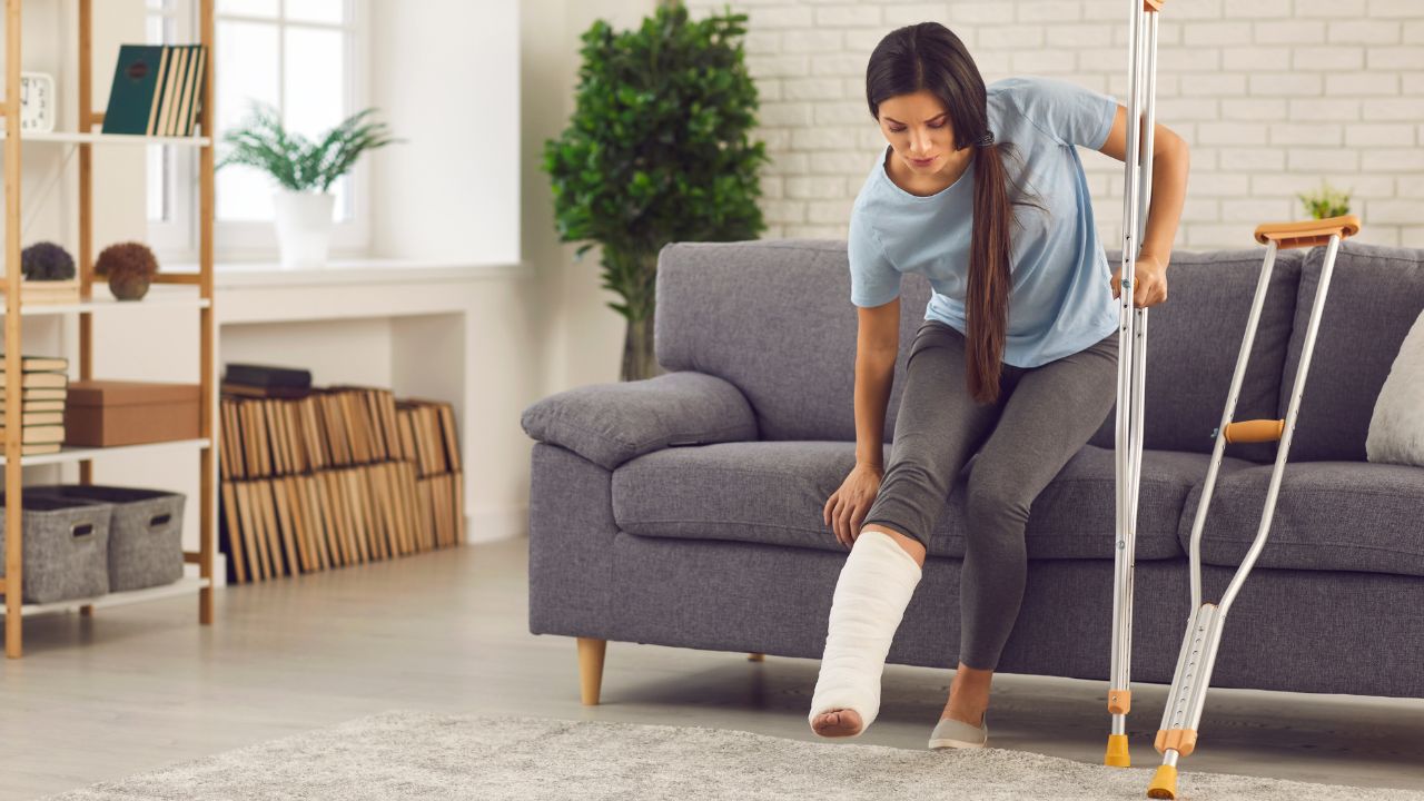 woman with a cast on and crutches getting up off of couch