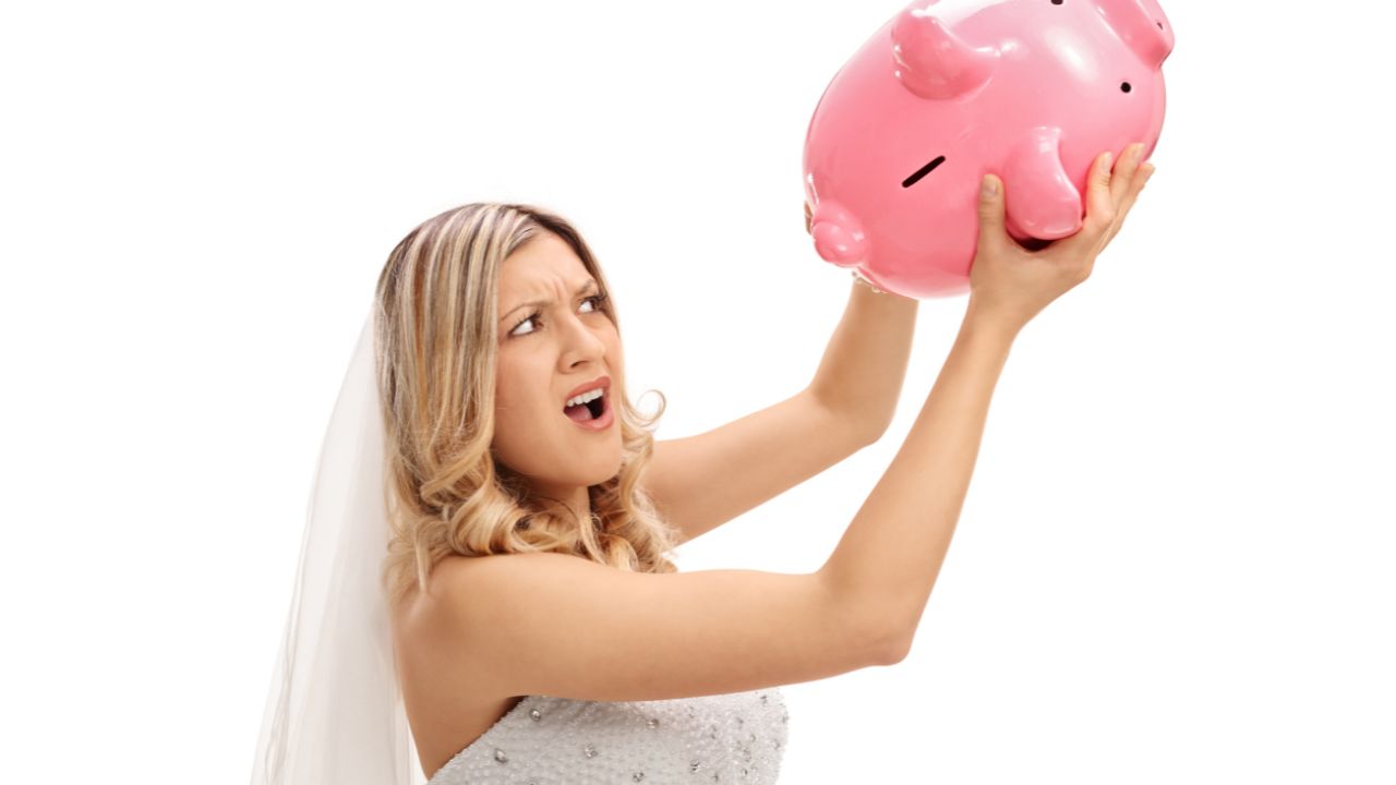 bride holding big pink piggy bank up and emptying it