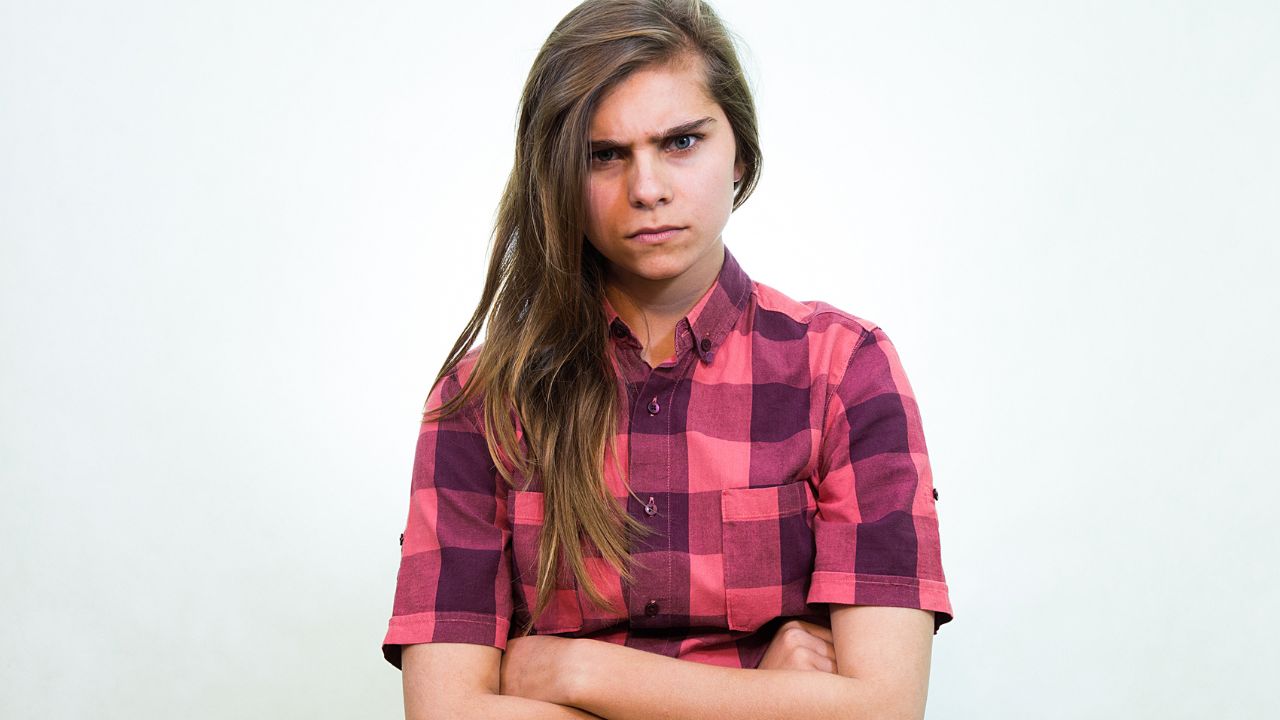 angry teenager with arms crossed and scowl on face