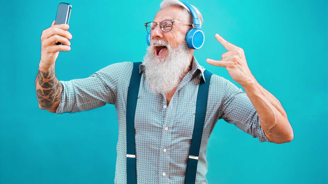 boomer aged man wearing headphones and holding a phone, video chatting