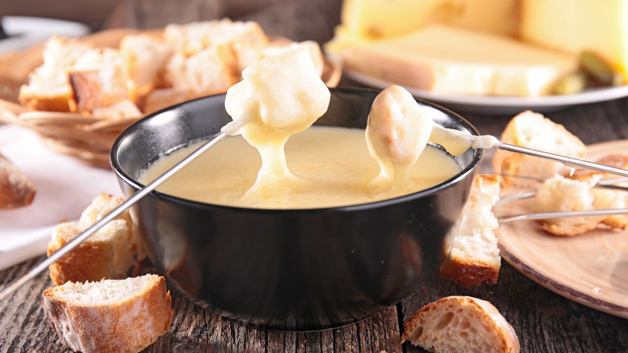 cheese fondu in a bowl with chunks of break being dipped