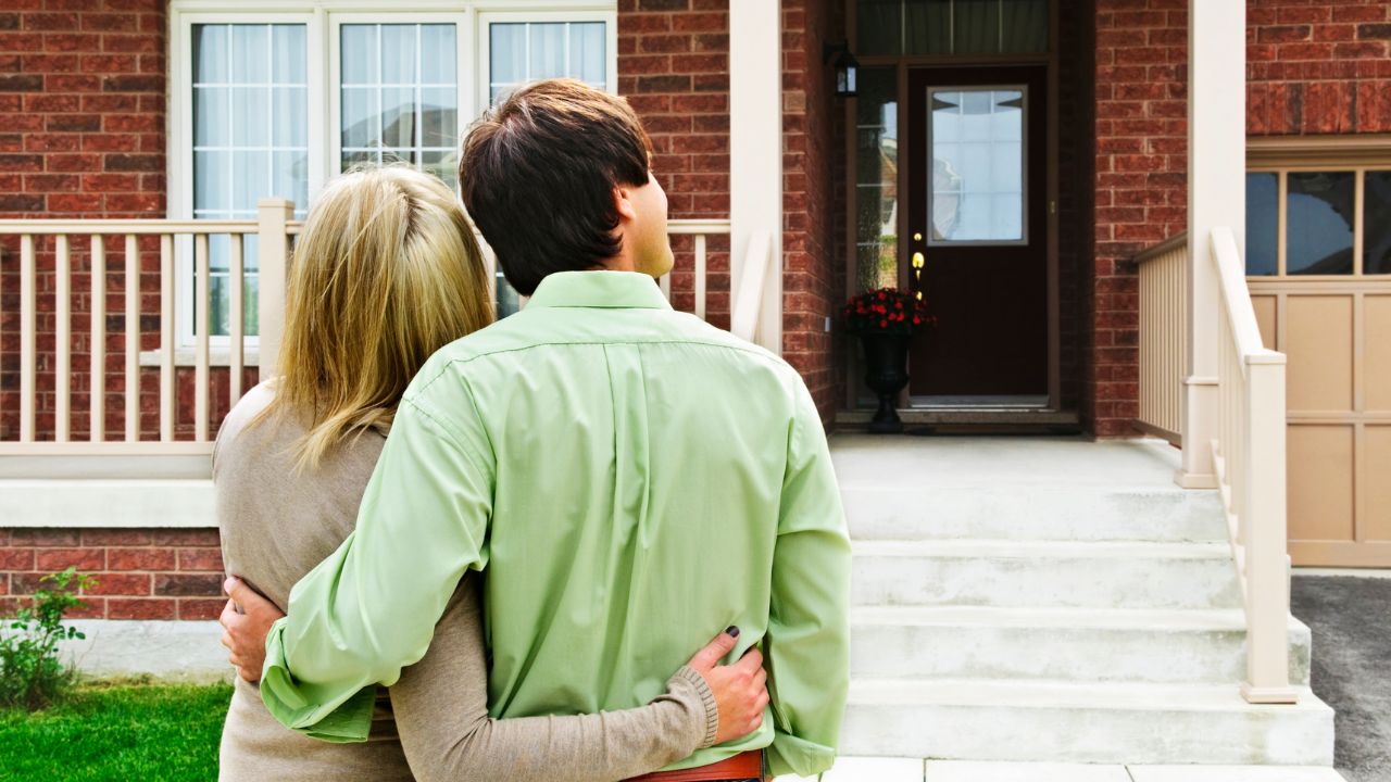 a couple holding each other and looking at a house